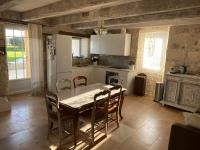 a kitchen with a table and chairs and a white refrigerator at Maison d hôtes Les Chantours dans réserve naturelle 15 hectares in Saint-Antoine-Cumond