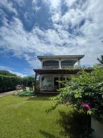 a house with a green yard with a sky at Appartement Coeur de Papillon in Baie-Mahault