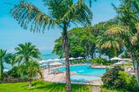 a pool at the resort with palm trees and the ocean at Lake Kivu Serena Hotel in Gisenyi