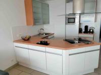 a kitchen with white cabinets and a wooden counter top at Superbe Appartement Vue Mer T3 70m2 in Mauguio