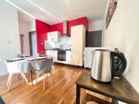 a living room with a table and a kitchen with red walls at Le Calypso, superbe T3+Parking proche du centre in Poitiers