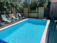 a large swimming pool with chairs and a fence at Villa 200m2, 3 suites, patio avec salle jeux, 1 piscine CHAUFFE DE DEBUT AVRIL A FIN OCTOBRE in Maruéjols