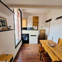 ein Wohnzimmer mit einem Tisch und einer Küche in der Unterkunft Au chant des mouettes in Cabourg