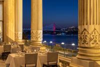 Un restaurante con mesas y sillas y vista a un puente. en Çırağan Palace Kempinski Istanbul, en Estambul