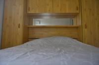 a bed in a room with wooden walls and wooden cabinets at Le Cottage de la Baie - vue mer en Baie de Somme in Woignarue