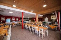 un ristorante con tavoli in legno e sedie bianche di Villa Gasparina a Ronchi