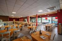 un ristorante con tavoli in legno e sedie bianche di Villa Gasparina a Ronchi