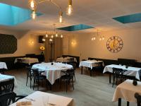 Un restaurante con mesas y sillas y un reloj en la pared. en Restaurant Hotel Logis Chez Sophie, en Briouze