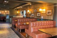 um restaurante com poltronas de couro marrom e um bar em An Chúirt Hotel, Gweedore, Donegal em Gweedore