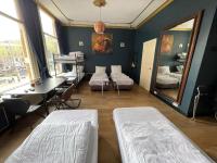 Zimmer mit 2 Betten, einem Tisch und einem Spiegel in der Unterkunft Amsterdam Rembrandt Square city center Hotel in Amsterdam