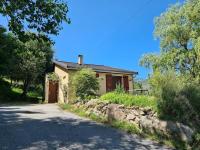 a small house with a stone wall next to a road at Chalet Le Parc de Latour, au pied de la montagne in Latour-de-Carol