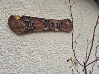 a wooden sign on a wall with a pair of scissors at Chalet Le Parc de Latour, au pied de la montagne in Latour-de-Carol