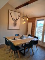 a dining room table with chairs and a deer picture on the wall at Chalet Le Parc de Latour, au pied de la montagne in Latour-de-Carol