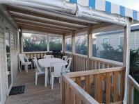 a wooden deck with a table and chairs on it at Mobil Home tout confort aux Charmettes in Les Mathes