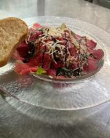 a salad on a glass plate with a slice of bread at Hotel-Restaurant Gasthaus Bonimeier in Niedergottsau