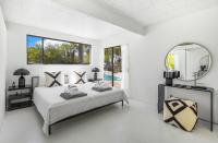 ein weißes Schlafzimmer mit einem Bett und einem Spiegel in der Unterkunft Former Steve McQueen’s home in Palm Springs