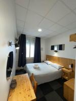 a bedroom with a bed and a table and a desk at Hôtel Le National in Saint-Étienne