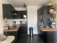 eine Küche mit schwarzen Schränken und einer Arbeitsplatte in der Unterkunft Grand Appartement Proche Paris Idéal Paris 2024 in Ivry-sur-Seine