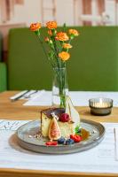 a plate with a piece of cake on a table with flowers at NOVY Hotel in Zielona Góra