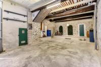 an empty garage with a green door and stone walls at Le Grappillon in Fitou