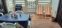 - une table bleue avec des chaises blanches et des fleurs sur la terrasse dans l&#39;établissement Maison de la plage, à Valras-Plage