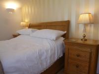 a bedroom with a bed and a nightstand with two lamps at Garden Suite in Rhuddlan
