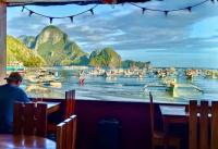 a man sitting at a table with a view of the water at La Salangane Beach Hotel - Downtown in El Nido