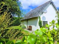 a white cottage with a bench in front of it at Le gîte des Jardins d&#39;Hayden in Courson