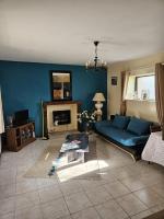 a living room with a blue couch and a fireplace at Le gîte des Jardins d&#39;Hayden in Courson