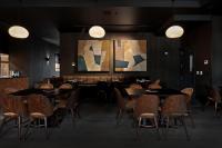 a dining room with tables and chairs and paintings at Abstract Hotel in Auckland