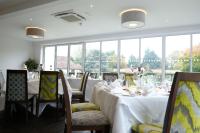 Un comedor con mesas y sillas blancas y ventanas. en Best Western Priory Hotel, en Bury Saint Edmunds