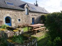 a wooden picnic table in front of a stone building at Gîte de l&#39;Hirondelle bleue in Brech