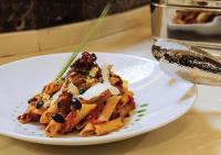 Un plato de pasta con aceitunas negras sobre una mesa. en فندق سفن روزز, en Amán