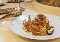 Un plato de comida con espaguetis en una mesa. en فندق سفن روزز, en Amán