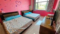 a bedroom with two beds and a pink wall at Sea Front Homestay in Magong