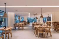 um restaurante com mesas e cadeiras de madeira e janelas em SKYLA Studios & Suites - Kondapur em Hyderabad