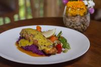 eine weiße Platte mit einem Stück Fisch und Gemüse in der Unterkunft The Alena Resort a Pramana Experience in Ubud