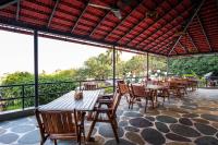 een restaurant met houten tafels en stoelen en ramen bij The Lighthouse - Formerly known as Utan Sea Resort in Thane