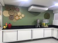 Pousada Jardins Tropical في بورتو دي غالينهاس: مطبخ بخزائن بيضاء وقبعات معلقة على الحائط