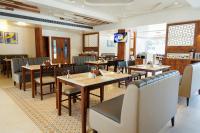 Un comedor con mesas y sillas de madera. en AJ GRAND ELITE HOTEL, en Mangalore