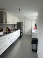 a large kitchen with white cabinets and a refrigerator at Maison avec piscine in Bièvres