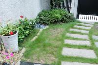 a garden with grass and flowers and a stone walkway at EZE Homestay in Ji&#39;an