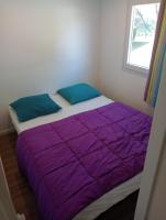Ce lit se trouve dans un dortoir doté d&#39;une couette violette et d&#39;une fenêtre. dans l&#39;établissement Camping du Lac, à Foix