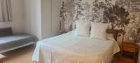 a bedroom with a bed with white sheets and a chair at Le Porteur de Glace Classé 2 étoiles in Aulus-les-Bains