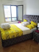 a large bed with yellow sheets and pillows in a bedroom at BEAU APPARTEMENT in Suresnes