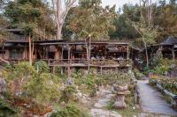 un bâtiment avec des personnes assises dans un jardin dans l'établissement ธารทอง ลอดจ์ Tharnthong Lodge, à Ban Pang Champi