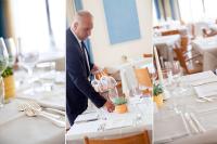 Un hombre con traje está sirviendo vino en una mesa. en Hotel Metropol, en Diano Marina