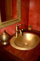 a bathroom sink with a gold faucet and a mirror at Le Clos des Laurons in Nyons