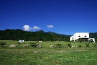 a white house in a field with mountains in the background at The Blue Lagoon B&amp;B in Fengbin