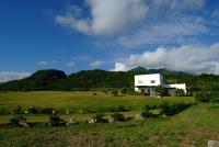 a white house in a field with sheep in the grass at The Blue Lagoon B&amp;B in Fengbin